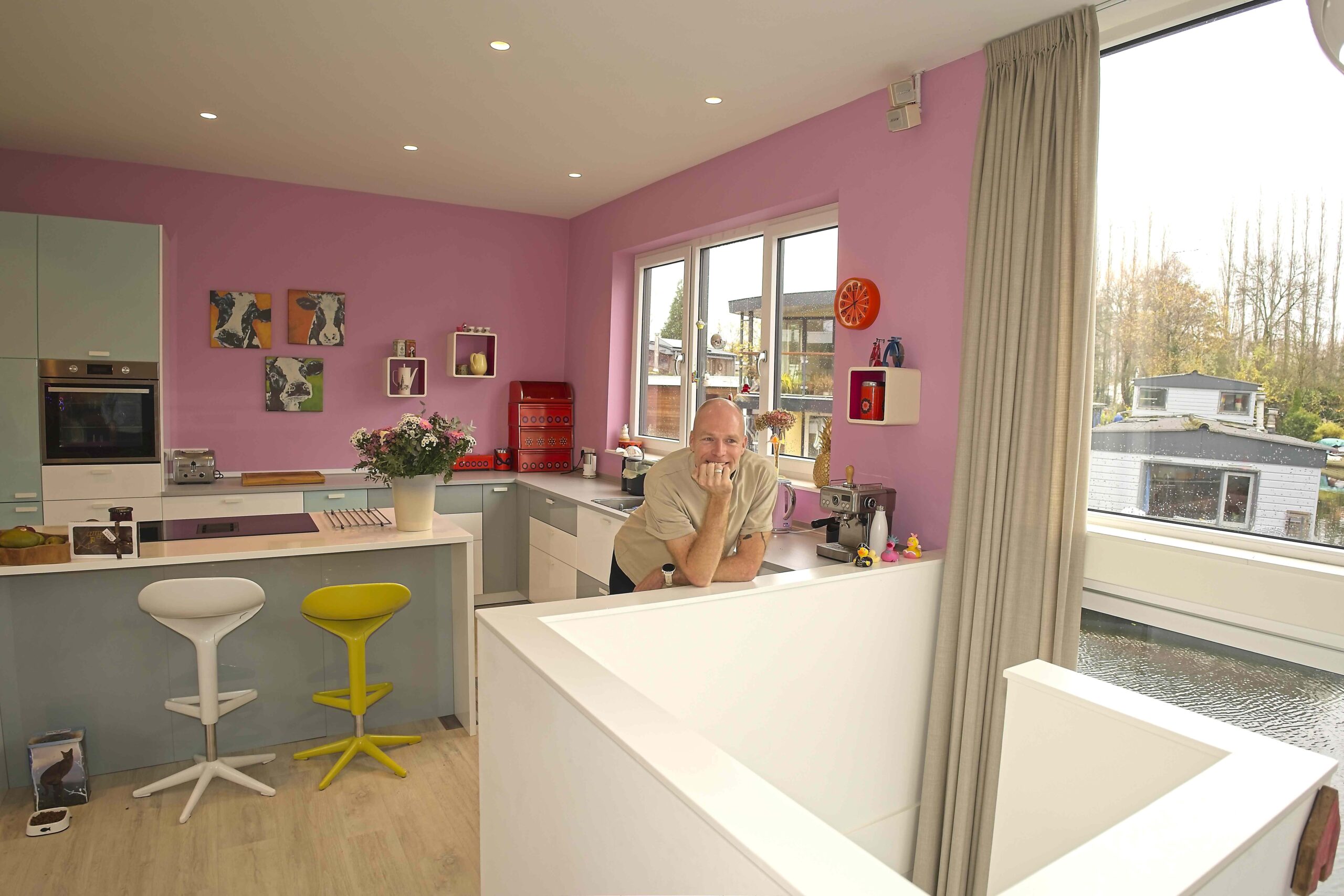 Jeroen in kleurrijke keuken met roze muur in zijn woonark Friendship IJsbaanpad Amsterdam